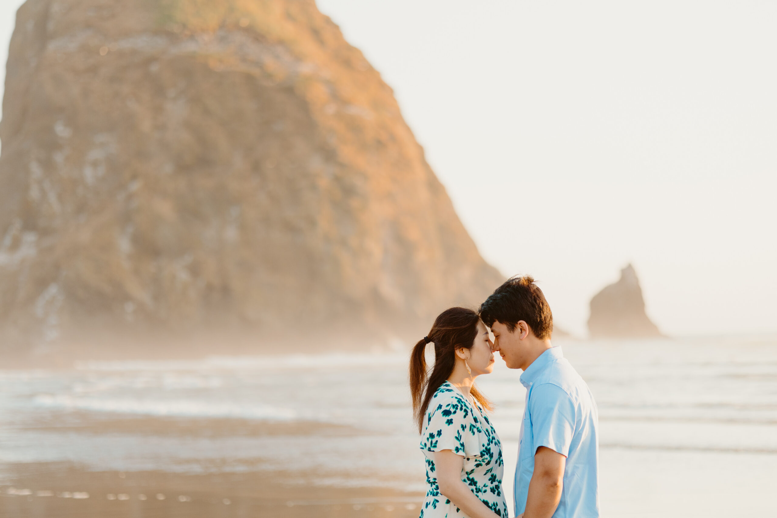 A man and a woman on cannon beach in front of haystack rock